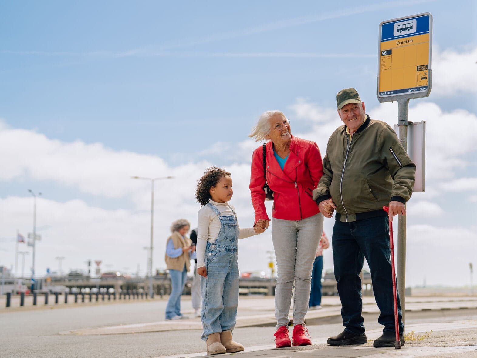 Opa en oma staan met kleinkind bij bushalte
