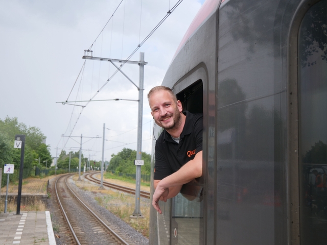 Trein machinist hangt uit het raam en glimlacht naar de camera