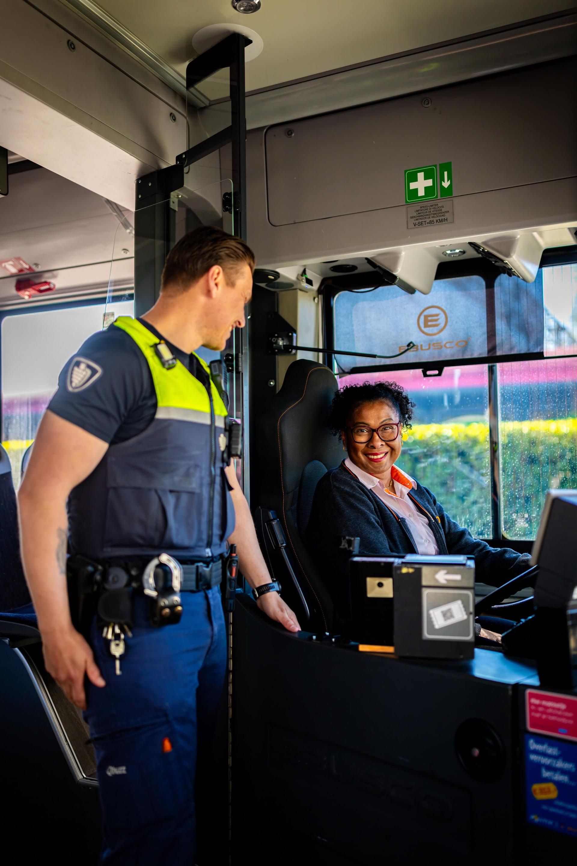 Service en veiligheid medewerker en buschauffeuse in gesprek met elkaar
